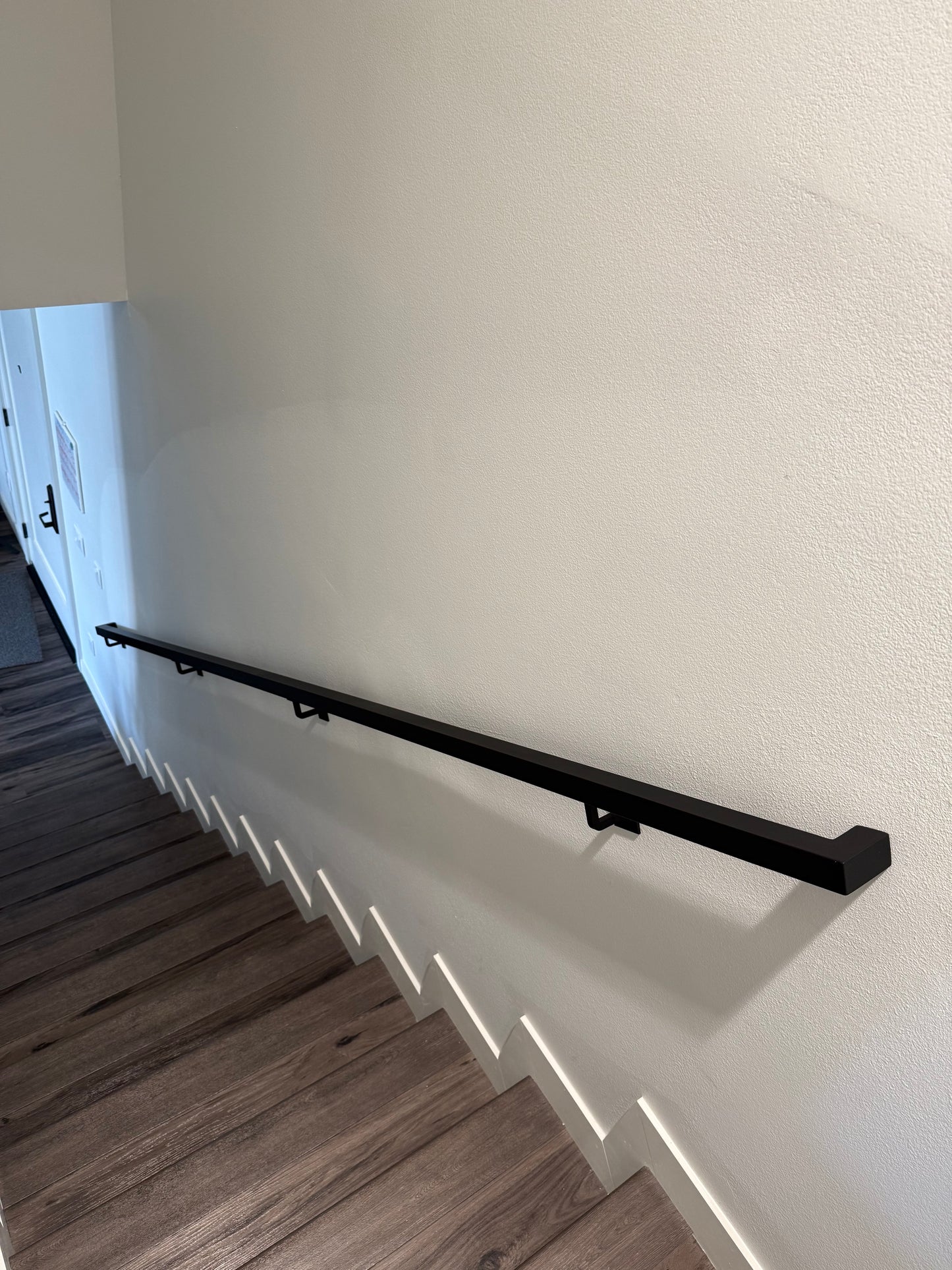view looking down a flight of 12 stairs at the 1.5"x1.5" Metal Handrail running from the top to the bottom