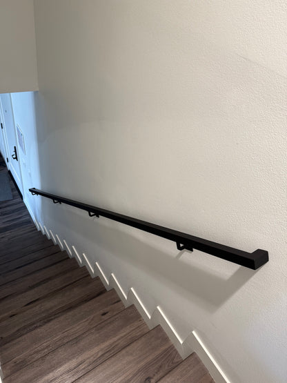view looking down a flight of 12 stairs at the 1.5"x1.5" Metal Handrail running from the top to the bottom
