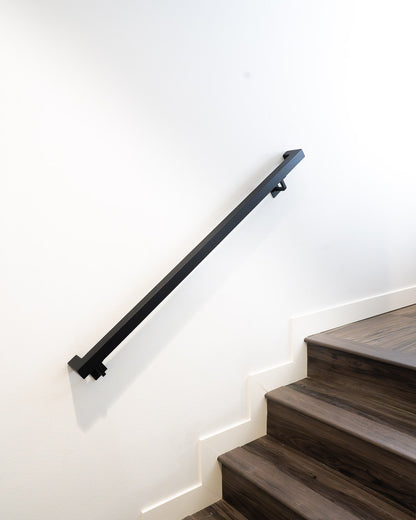 5ft 1.5"x1.5" Handrail mounted on white wall above brown steps