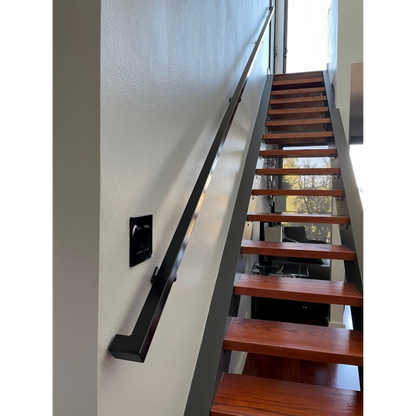 1.5"x1.5" Metal Handrail mounted on a white wall above floating, wooden steps with large, glass windows on the upper and lower levels in the background